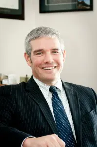 A man in suit and tie smiling for the camera.