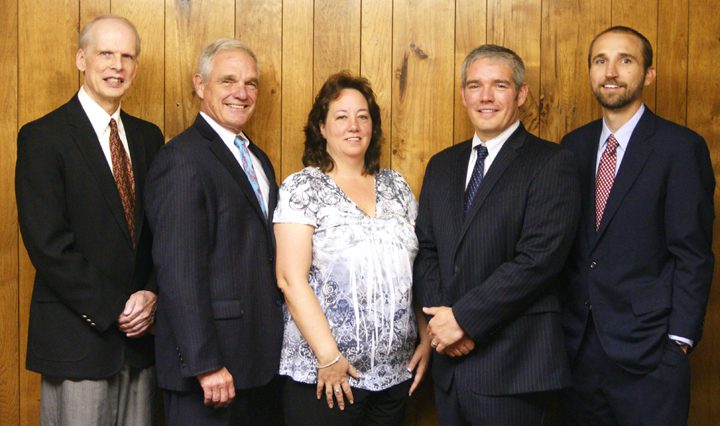 A group of people standing in front of a wooden wall.